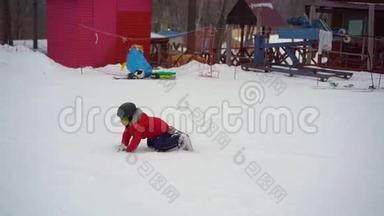 小男孩在滑雪板的第一课上摔倒了。 冬季活动概念。 慢镜头